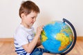 Cute five year old boy shows finger on globe