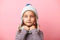 Cute five years little girl on pink background, wears beautiful winter hat and scarf.