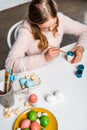 Cute focused child painting easter egg at table