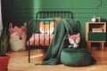 Cute fox toy on velvet emerald pouf next to metal bed in teenager`s bedroom Royalty Free Stock Photo