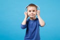 Cute fun kid boy 4 years old wearing blue t-shirt clothes listen music in headphones isolated on blue wall background Royalty Free Stock Photo