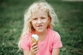 Cute funny adorable girl with dirty nose and milk moustaches eating licking ice cream from waffle cone. Child eating tasty sweet Royalty Free Stock Photo