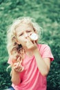 Cute funny adorable girl with long blonde messy hair eating licking ice cream from waffle cone. Child eating tasty sweet cold Royalty Free Stock Photo