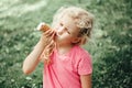 Cute funny adorable girl with long messy blonde hair eating licking ice cream from waffle cone. Child eating tasty sweet cold Royalty Free Stock Photo