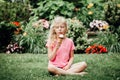 Cute funny adorable girl sitting on grass in park eating licking ice cream from waffle cone. Child eating tasty sweet cold summer Royalty Free Stock Photo