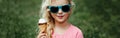 Cute funny adorable girl in sunglasses with dirty nose and moustaches eating ice cream from waffle cone. Happy cool hipster child Royalty Free Stock Photo