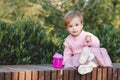 Cute funny baby girl 1 year old wear pink dress sitting with plastic bottle with water Royalty Free Stock Photo