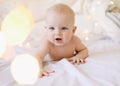 Little child doing tummy time. Adorable baby learning to crawl in white  bedroom. Cute funny baby lying under the blanket on bed. Royalty Free Stock Photo