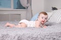 Cute funny baby in white lies on bed with pillows