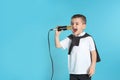 Cute funny boy with microphone on color background. Royalty Free Stock Photo