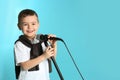 Cute funny boy with microphone on color background. Royalty Free Stock Photo