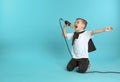 Cute funny boy with microphone on color background. Royalty Free Stock Photo