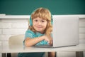 Cute funny child using laptop computer, kid boy studying through online e-learning. Little funny system administrator. Royalty Free Stock Photo