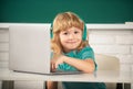 Cute funny child using laptop computer, kid boy studying through online e-learning. Little funny system administrator. Royalty Free Stock Photo