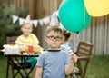 Cute funny four year old boy celebrating his birthday with family or friends in a backyard. Birthday party. Kid wearing Royalty Free Stock Photo