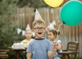 Cute funny four year old boy celebrating his birthday with family or friends in a backyard. Birthday party. Kid wearing Royalty Free Stock Photo