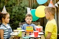 Cute funny four year old boy celebrating his birthday with family or friends, blowing candles on homemade baked cake in a backyard Royalty Free Stock Photo