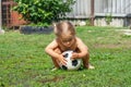 Cute funny girl child playing soccer ball in the backyard on a summer sunny day. A child rides a soccer ball on the yard Royalty Free Stock Photo