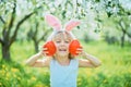 Cute funny girl with Easter eggs and bunny ears at garden. easter concept. Laughing child at Easter egg hunt