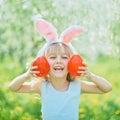 Cute funny girl with Easter eggs and bunny ears at garden. easter concept. Laughing child at Easter egg hunt