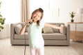 Cute funny girl with microphone in room