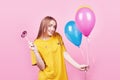 Cute funny girl portrait holds an air colorful balloons and lollipop smiling on pink background. Beautiful multicultural Royalty Free Stock Photo