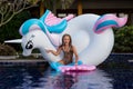 Cute funny girl sitting chilling on inflatable ring unicorn. Kid child enjoying having fun in swimming pool. Summer outdoor water