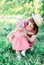 Cute funny happy baby making his first steps on a green grass, mother holding her hands supporting by learning to walk Royalty Free Stock Photo