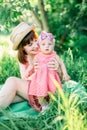 Cute funny happy baby making his first steps on a green grass, mother holding her hands supporting by learning to walk Royalty Free Stock Photo