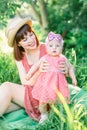 Cute funny happy baby making his first steps on a green grass, mother holding her hands supporting by learning to walk Royalty Free Stock Photo