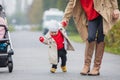 Cute funny happy baby making his first steps on a green lawn in autumn garden, mother holding his hands supporting by learning to Royalty Free Stock Photo