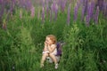 A cute funny happy red-haired girl is sitting on a basket of flowers and smiling gently. Royalty Free Stock Photo