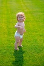 Cute funny laughing baby learning to crawl, having fun playing on the lawn watching summer in the garden. Happiness and Royalty Free Stock Photo