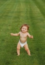 Cute funny laughing baby learning to crawl, having fun playing on the lawn watching summer in the garden. Little fun Royalty Free Stock Photo