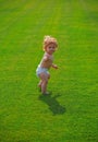 Cute funny laughing baby learning to crawl wearing a diaper having fun playing on the lawn watching summer in the garden Royalty Free Stock Photo