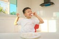 Cute funny little Asian boy sitting in the kitchen with a marshmallow at home, Unhealthy kids snacks Royalty Free Stock Photo