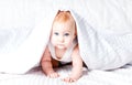 Cute and funny little baby smiling under white blanket. Copy spa Royalty Free Stock Photo