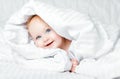 Cute and funny little baby smiling under white blanket. Copy spa Royalty Free Stock Photo