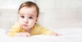 Cute funny little child lying on bed on white background with copy space. little baby girl learning to crawl and playing in bedroo Royalty Free Stock Photo