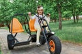 Cute funny little girl with pigtails wearing casual clothing and baseball cap riding tricycle wearing enjoying nice sunny day in Royalty Free Stock Photo