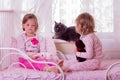 Cute funny little girls (sisters) play in bed, on the window sit Royalty Free Stock Photo