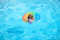 Cute funny little toddler boy in a colorful swimming suit and sunglasses relaxing with toy ring floating in a pool Royalty Free Stock Photo