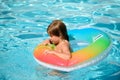 Cute funny little toddler boy relaxing with toy ring floating in a swimming pool having fun during summer vacation in a Royalty Free Stock Photo