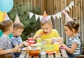 Cute funny nine year old boy celebrating his birthday with family or friends and eating homemade baked pizza in a backyard.