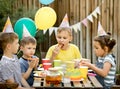 Cute funny nine year old boy celebrating his birthday with family or friends and eating homemade baked pizza in a backyard.