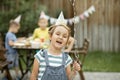 Cute funny six year old girl celebrating her birthday with family or friends in a backyard. Birthday party. Kid wearing Royalty Free Stock Photo