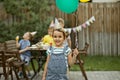 Cute funny six year old girl celebrating her birthday with family or friends in a backyard. Birthday party. Kid wearing party hat Royalty Free Stock Photo