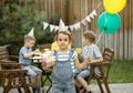 Cute funny six year old girl celebrating her birthday with family or friends in a backyard. Birthday party. Kid wearing party hat Royalty Free Stock Photo