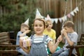 Cute funny six year old girl celebrating her birthday with family or friends in a backyard. Birthday party. Kid wearing party hat Royalty Free Stock Photo