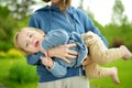 Cute funny toddler boy in his mothers arms. Mom and son having fun on sunny summer day in a park. Adorable son being held by mommy Royalty Free Stock Photo